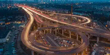 Modern highway interchange with city skyline at dusk, symbolizing infrastructure development.
